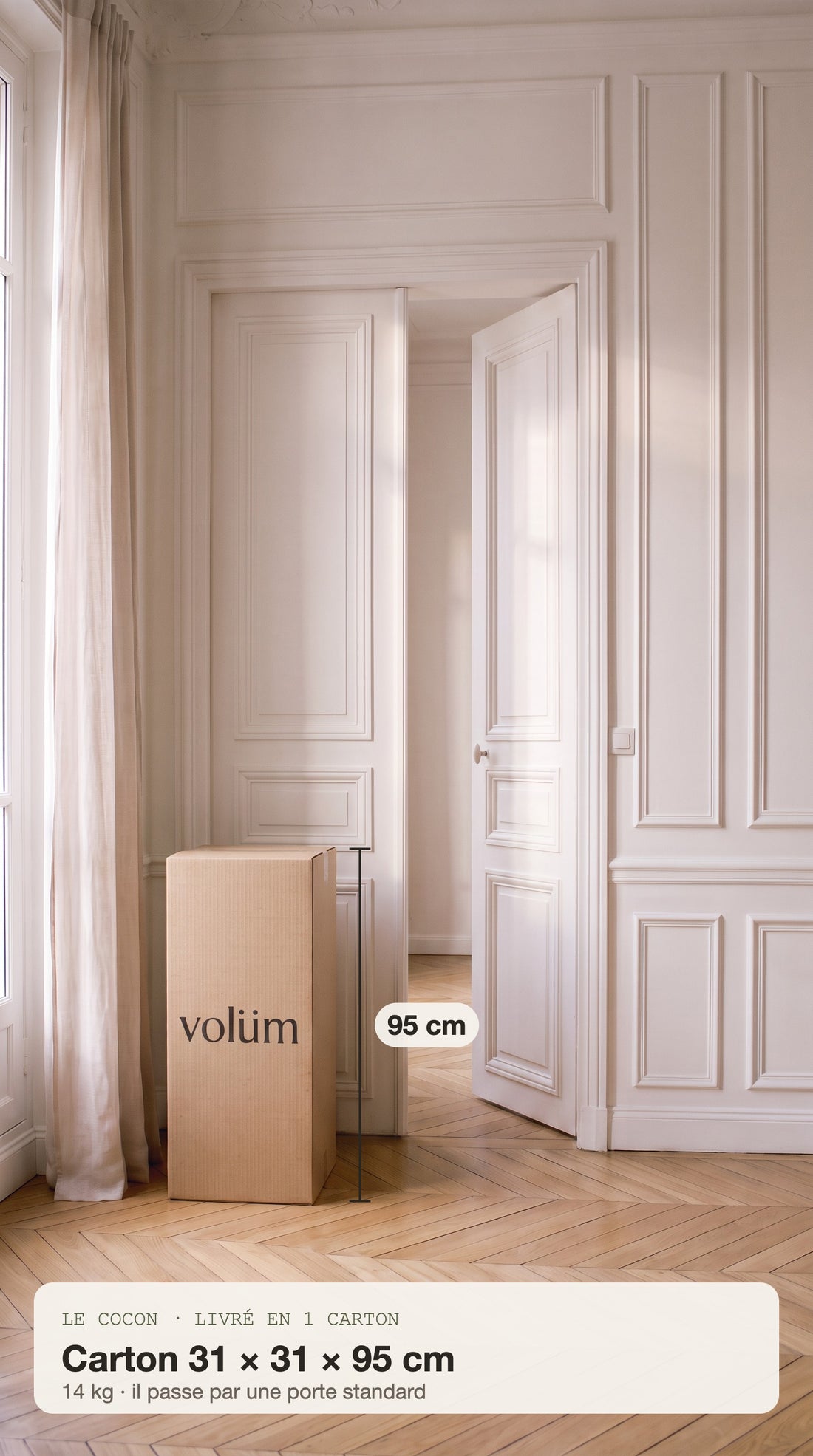 Le carton du Cocon, 31 × 31 × 95 cm, posé à côté de la porte du salon